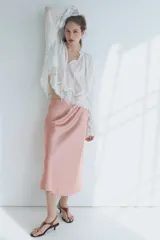 Pollera midi de tiro alto, confeccionada en tela satinada de color rosado con caída suave y leve vuelo en el bajo.