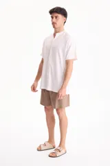 Camisa de lino de manga corta, color blanco, con cuello mao y cierre frontal de botones.