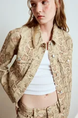 Cazadora de cuello solapa y manga larga con estampado animal print de serpiente, bolsillos con solapa en el pecho y cierre frontal con botones metálicos.