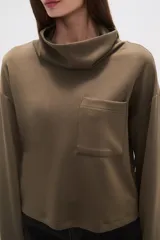 Buzo de cuello alto tipo polera, color verde oliva, con corte holgado, mangas largas y un bolsillo frontal aplicado en el pecho.