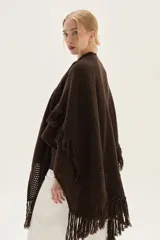 Ruana tejida en lana de cordero con diseño de sectores calados y terminación con flecos en los bordes.