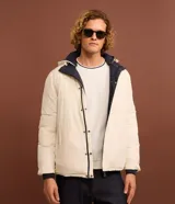 Campera puffer de hombre reversible, con diseño acolchado, cuello alto, capucha y cierre frontal.