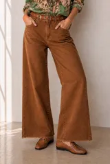 Jean de corte wide leg en color marrón, con diseño de tiro medio, bolsillos clásicos y terminación desmechada en el bajo.