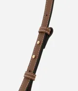 Cartera tipo baguette mediana con cierre de cremallera, correa de mano ajustable y estampado de rayas verticales en tonos beige y blanco. La base de la cartera es de color marrón.