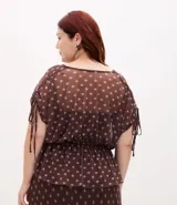 Blusa tipo bata confeccionada en tule con forro interior, escote en V, mangas cortas con detalle de lazo y cintura fruncida. Presenta un estampado geométrico tipo pañuelo.