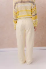 Pantalón de jean de tiro medio-alto y pierna amplia con caída recta, color amarillo manteca, con diseño clásico de cinco bolsillos y cierre delantero con botón.