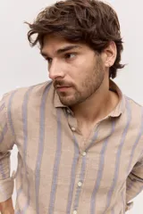 Camisa de manga larga de lino con diseño a rayas en tonos celestes y blancos, cuello camisero clásico y cierre frontal de botones.