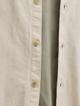 Sobrecamisa de manga larga color beige claro, con cierre frontal de botones, cuello camisero y un bolsillo aplicado en el pecho.