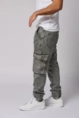 Pantalón jean gris claro, estilo jogger, con bolsillos cargo laterales y puños elásticos en los tobillos.