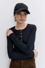 Remera de manga larga color negro, con cuello redondo y cierre frontal parcial con botones metálicos.