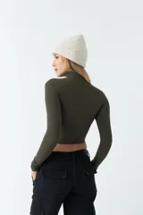 Polera de manga larga ajustada al cuerpo, confeccionada en tejido rib de algodón. Presenta cuello alto y diseño corto tipo crop top.