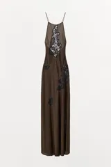 Vestido midi de corte al bies con cuello halter y tirantes finos. Presenta un diseño fluido en color marrón con aplicaciones de encaje a contraste en el frente y lateral. Cuenta con cierre lateral mediante cremallera oculta.