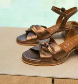 Sandalias de cuero color dorado, con plataforma y taco cuadrado. Presentan tiras cruzadas en el empeine y pulsera al tobillo con hebilla.