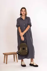 Mochila de nylon color verde oliva, con compartimento principal y bolsillo frontal con cierre metálico. Presenta detalles de cordones decorativos en los tiradores de los cierres, una grifa de goma con el logo de la marca y correas ajustables.