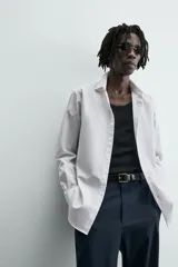 Camisa slim fit blanca de manga larga, cuello italiano y puños con botón. Cierre frontal de botonadura.