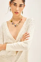Cardigan negro con escote en V, manga larga y cierre frontal con botones. Presenta un diseño con aplicación de tachas plateadas distribuidas por toda la prenda.