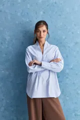 Camisa de calce relajado color celeste, con escote en V y cuello mao, mangas largas y largo extendido.