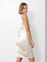 Vestido midi sin mangas de satén color champagne, con cintura elastizada, falda plisada y cruzada. Espalda con abertura central y cierre invisible.