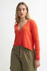 Cardigan de tejido de punto color gris claro, con escote en V profundo y cierre frontal de botones. Presenta mangas largas con puños acanalados y un calce ligeramente holgado.