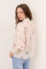 Camisa de manga larga color arena con delicado estampado floreado, cuello mao con volados, escote en V con botones frontales y puños fruncidos elastizados.