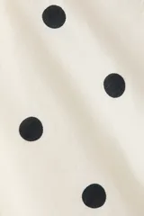 Vestido corto de lunares color blanco, con tiras finas cruzadas en la espalda, escote con volados y bajo asimétrico con detalles de volados largos.