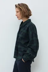 Camisa de manga larga con estampado de cuadros en tonos verde y azul marino, cuello clásico y cierre frontal con botones.