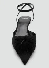 Zapato de tacón kitten color negro, con punta fina, tira ajustable al tobillo con hebilla y detalle de aplicación floral con flecos en el empeine.
