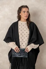 Ruana abierta de color beige, confeccionada en tejido de punto con terminación de flecos en el ruedo.