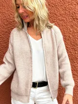Campera de tejido de punto en color beige melange, con cierre frontal completo, cuello alto y mangas largas con puños acanalados.