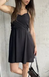 Vestido corto negro con breteles finos y escote cruzado.