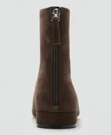 Botín de caña baja confeccionado en piel de serraje, con punta redonda, suela plana y cierre de cremallera en la parte posterior.