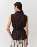 Camisa sin mangas color negro de algodón, con cuello camisero, cierre frontal de botones y lazo ajustable en la cintura.