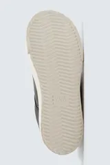 Zapatilla deportiva de estilo retro con parte superior de cuero sintético y suela de plataforma con diseño irregular y texturizado.