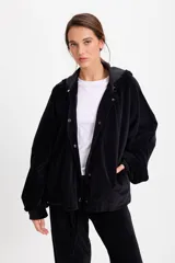 Campera de terciopelo color chocolate, con corte holgado, mangas murciélago y capucha desmontable. Presenta cierre frontal con botones a presión y bolsillos laterales.