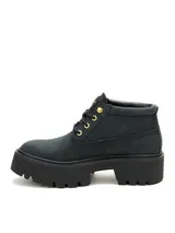 Bota tipo chukka de Caterpillar, color negro, con plataforma dentada y suela de goma. Presenta cordones negros, ojales metálicos dorados y el logo de la marca en el lateral y la lengüeta.