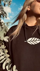 Hoodie negro con cordones ajustables y estampado de una hoja blanca en el frente.