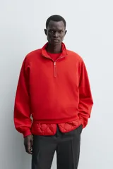 Sudadera de algodón ligero en color rojo, con cuello subido y cierre frontal de cremallera. Presenta mangas largas con puños acanalados y dobladillo inferior en rib.
