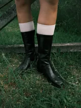 Bota de cuero negra, de caña media, punta cuadrada y taco bajo forrado.