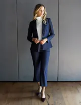 Blazer de tencel color azul marino con cuello de solapa y cierre frontal de un solo botón. Presenta bolsillos delanteros simulados con detalle de vivo trenzado y un diseño estructurado de calce entallado.