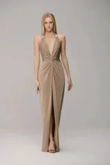 Vestido largo de fiesta color beige, con diseño de frente única, escote profundo en V y detalle de nudo en la cintura. Presenta una falda fluida con tajo frontal central.