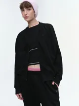 Campera deportiva estilo bomber color negro, con cierre frontal, cuello redondo acanalado y mangas raglán. Presenta puños y bajo elásticos, y bolsillos frontales.
