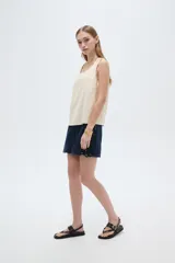 Musculosa de viscosa color beige claro, holgada, con cuello redondo y tirantes anchos formados por múltiples tiritas trenzadas.