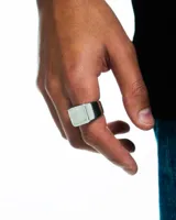 Anillo plateado de acero inoxidable con forma cuadrada y bordes redondeados.