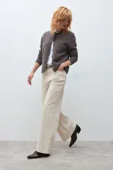Jean de corte wide leg en color beige claro, con tiro medio y cierre frontal con botón y cremallera. Presenta un diseño de cinco bolsillos y costuras reforzadas.