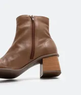 Bota de cuero de caña media para mujer, con punta cuadrada y tacón bloque de 6 cm. Presenta un cierre de cremallera en el lateral interno y una costura central decorativa en la parte frontal.