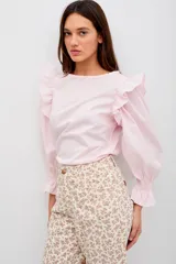 Blusa de algodón color rosado, con mangas largas abullonadas, volados en los hombros y puños elásticos con terminación en volado.