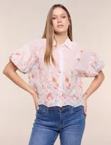 Camisa de gasa rosa con estampado floral y bordados, cuello camisero, mangas cortas abullonadas y cierre frontal de botones.