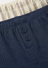 Pack de dos shorts de pijama de canalé con cintura elástica, cierre frontal con botones y terminación con volados sutiles en el ruedo. Incluye un short azul marino liso y otro de diseño a rayas.