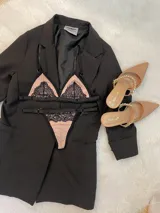 Conjunto de lencería compuesto por un corpiño triangular y una tanga, confeccionados en lycra color beige con detalles de encaje negro y elásticos a tono.