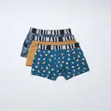 Pack de tres boxers de corte ajustado con cintura elástica ancha con la palabra Ultimate estampada. Incluye un modelo con estampado de hojas tropicales en tonos oscuros, un modelo liso en color tostado y un modelo con estampado de frutas en tonos azulados.